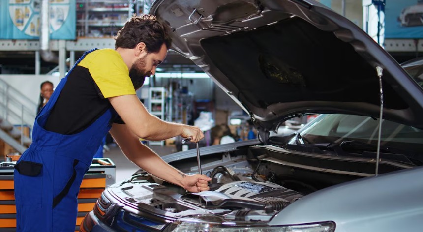 A man mechanic and woman customer look at the car hood and discuss repairs.